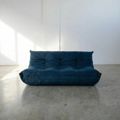 Bruma 3 seater sofa in dark blue Velvet Suede by vibehaus on a concrete floor, photographed from a front angle.