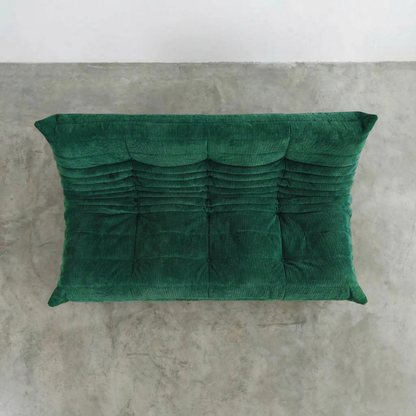 Bruma 3 seater sofa in dark green Corduroy by vibehaus on a concrete floor, photographed from a top angle.