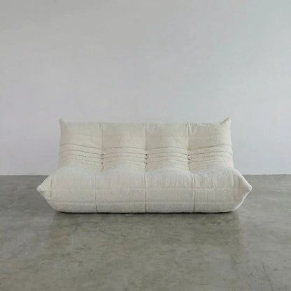 Bruma 3 seater sofa in white bouclé by vibehaus on a concrete floor, photographed from a front angle.