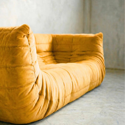 Bruma Sofa in yellow with armrests against a neutral wall