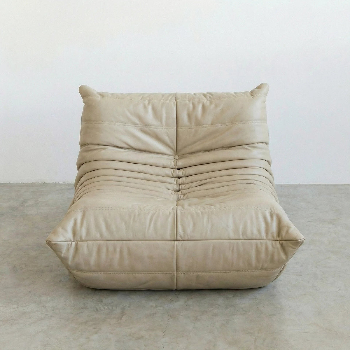 Bruma Chair in cream real cowhide leather on a concrete floor with a white wall background