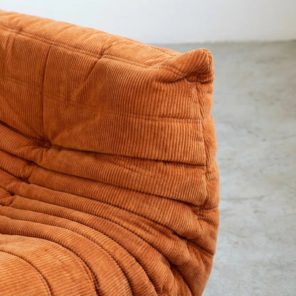 Close-up of an Bruma Sofa Corner in orange corduroy on a light gray background