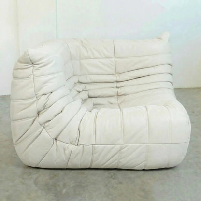 Bruma Corner Section in white leather on a concrete floor with a white wall background