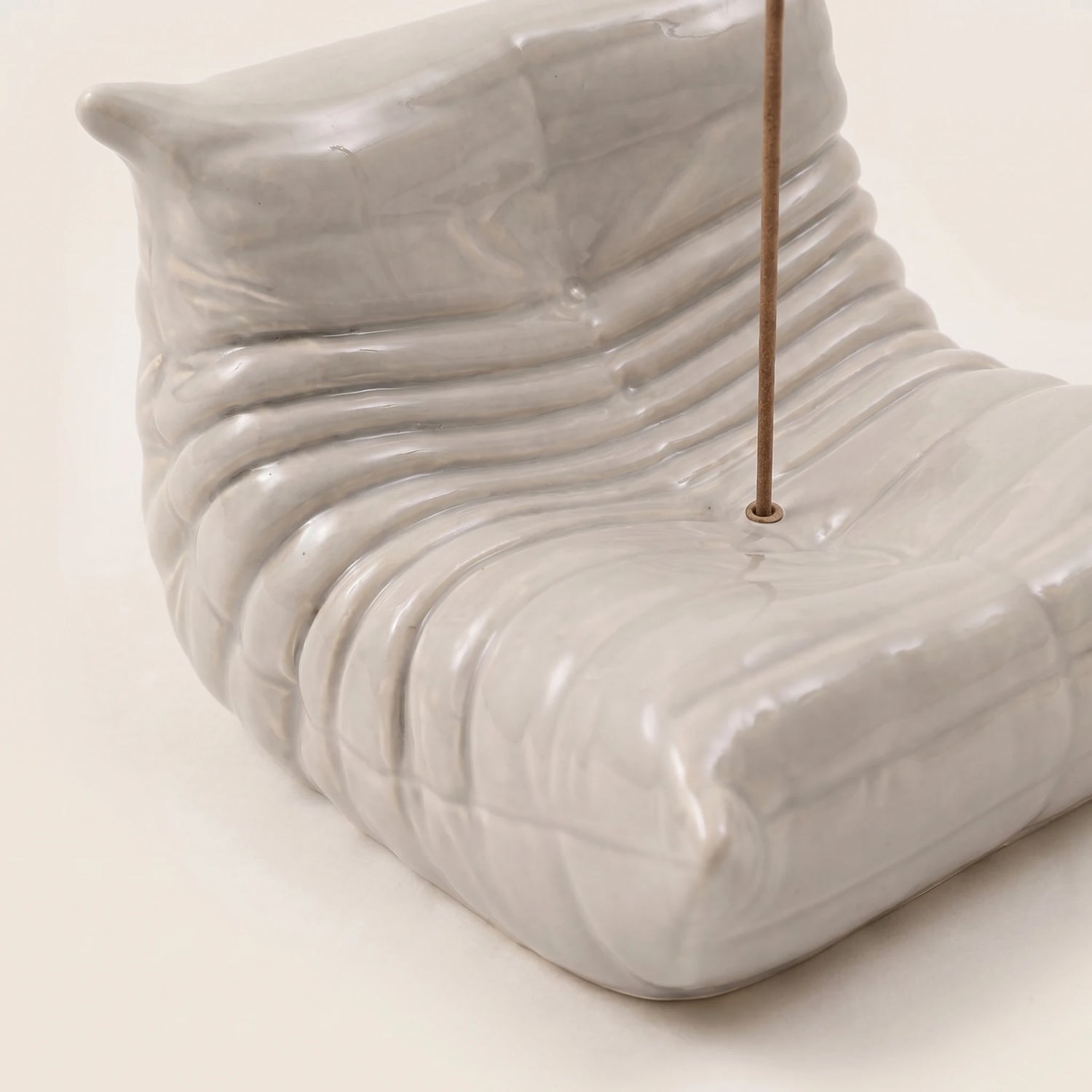 Close-up of the grey Bruma incense holder showing the hand-finished resin texture and sculptural lounge chair curves.