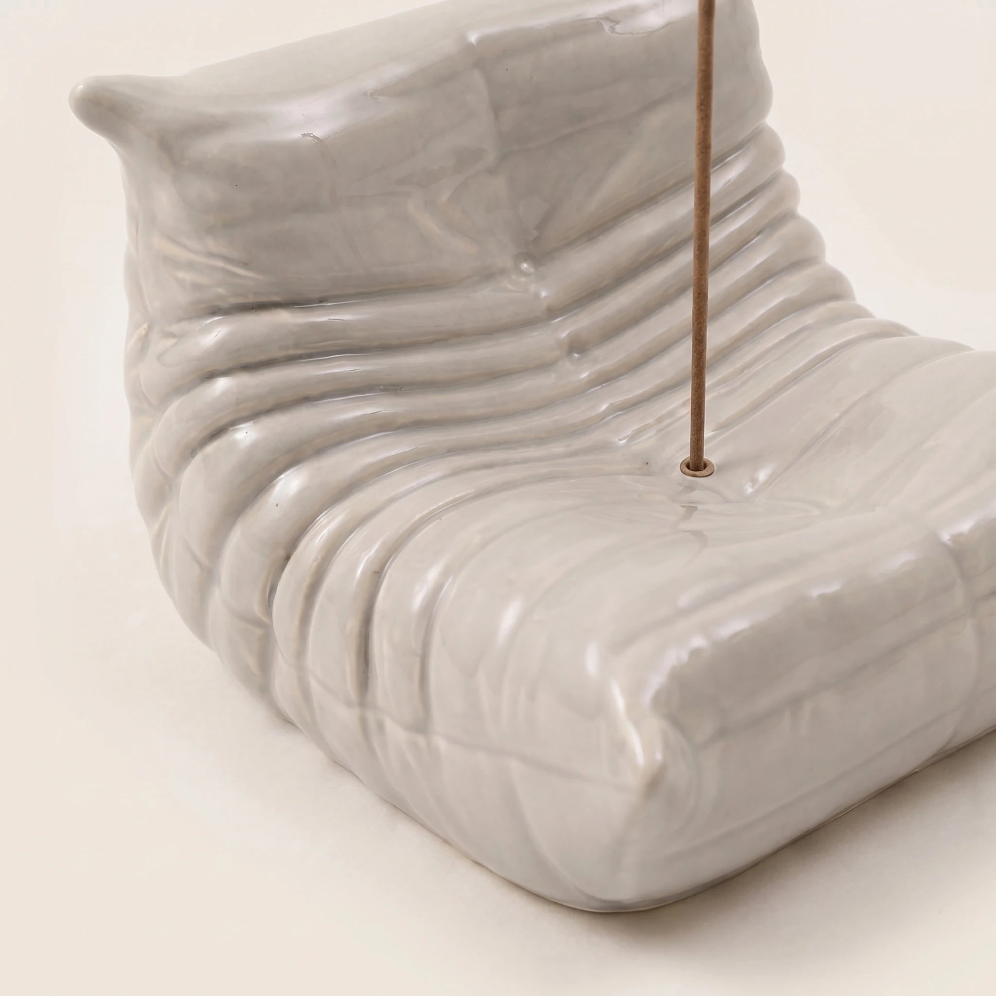 Close-up of the grey Bruma incense holder showing the hand-finished resin texture and sculptural lounge chair curves.
