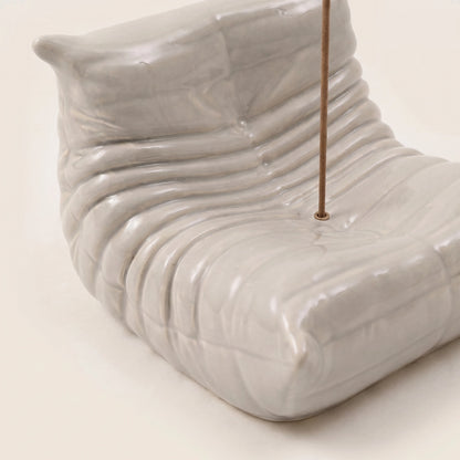 Close-up of the grey Bruma incense holder showing the hand-finished resin texture and sculptural lounge chair curves.