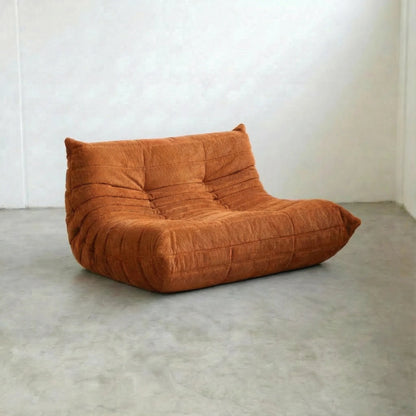 Bruma 2 Seater Sofa in orange corduroy,, on concrete floor, from a sideangle