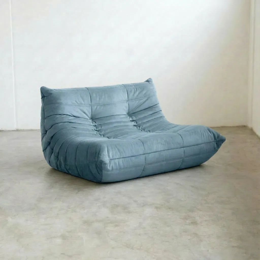 Light Blue Bruma Sofa in Velvet Suede on a concrete floor with a white wall background
