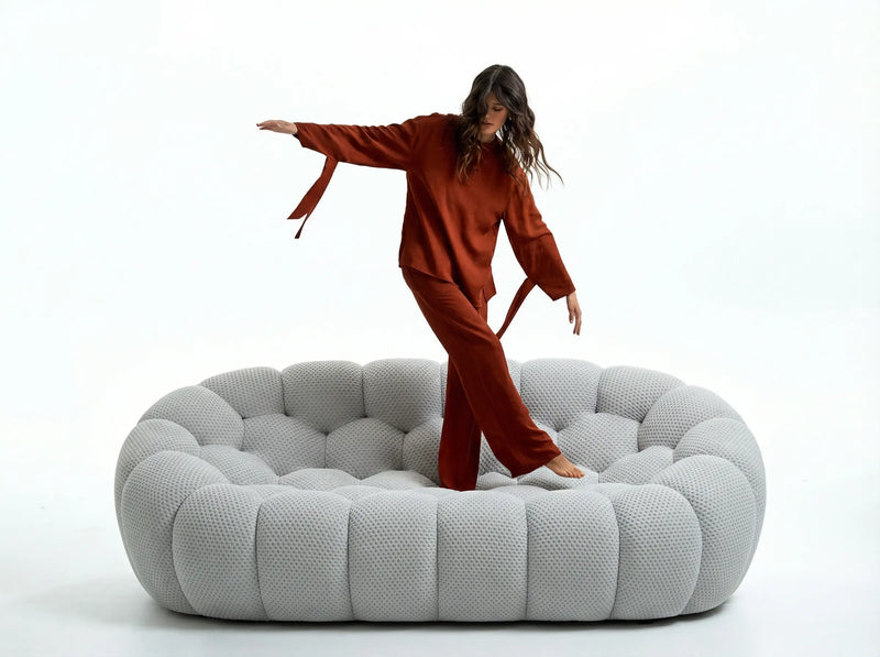 A women standing on the grey bubble sofa replica by vibehaus against a white background