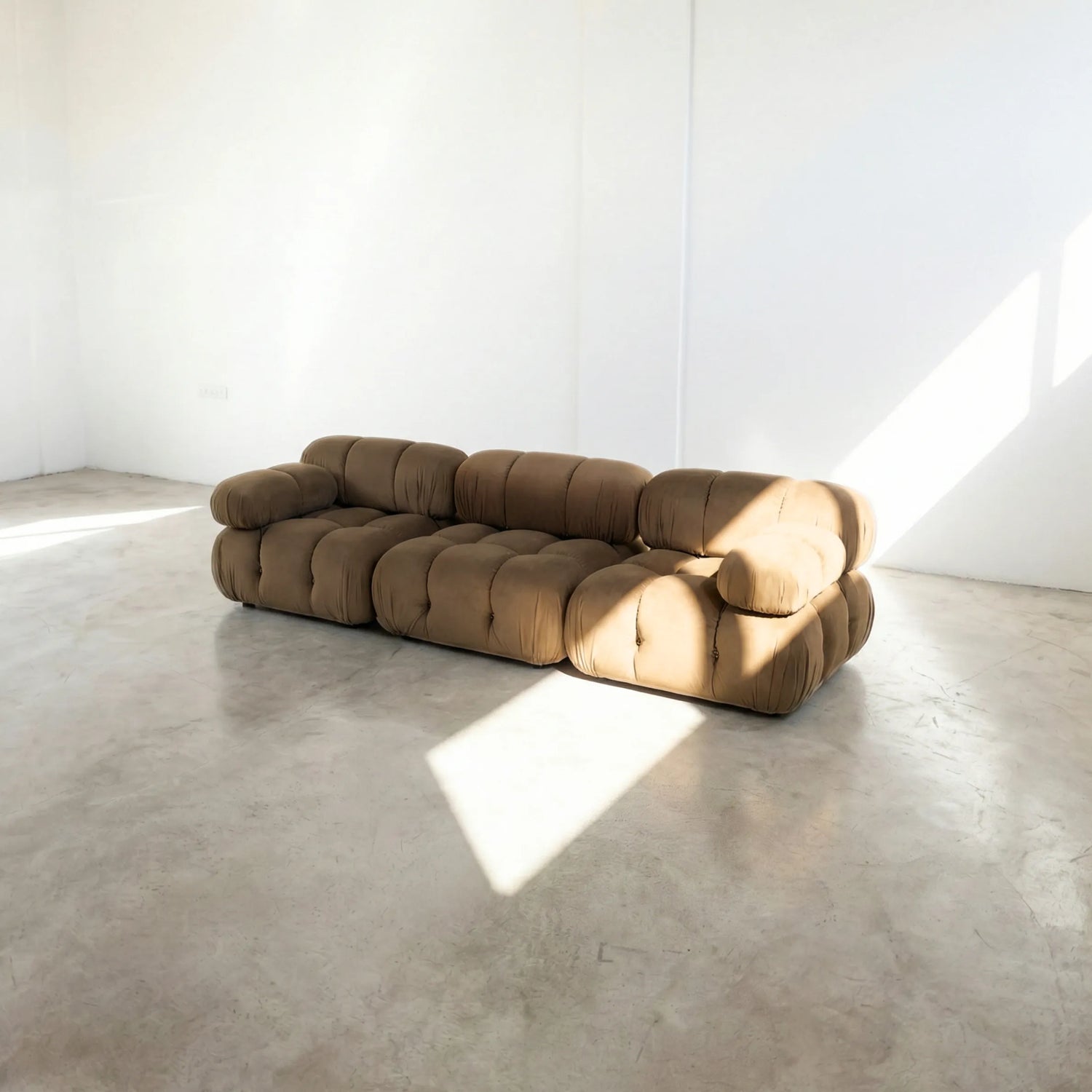 Brown camaleonda sofa dupe in a minimalistic room with concrete floor and white walls