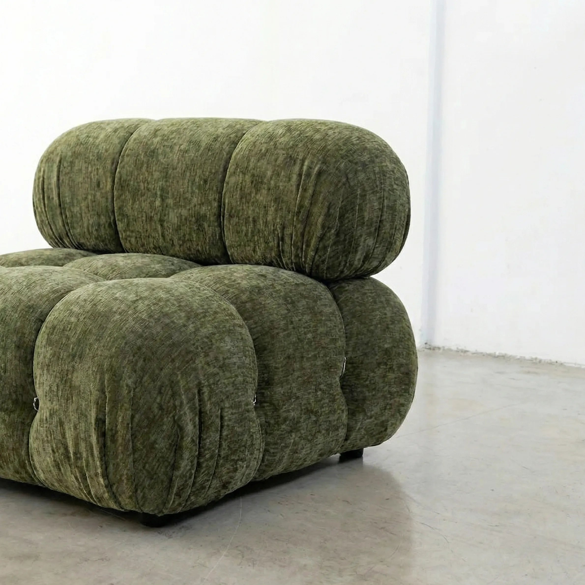 Green chenille camaleonda sofa dupe in a minimalistic room with white walls and gray floor.