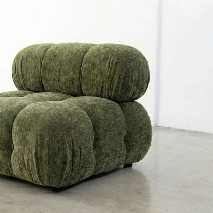 Green chenille camaleonda sofa dupe in a minimalistic room with white walls and gray floor.