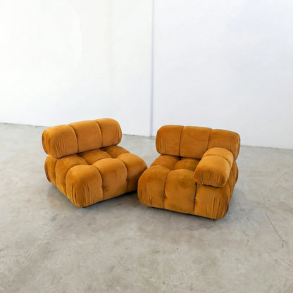 Two mustard yellow camaleonda dupe armchairs on a concrete floor with a white wall background