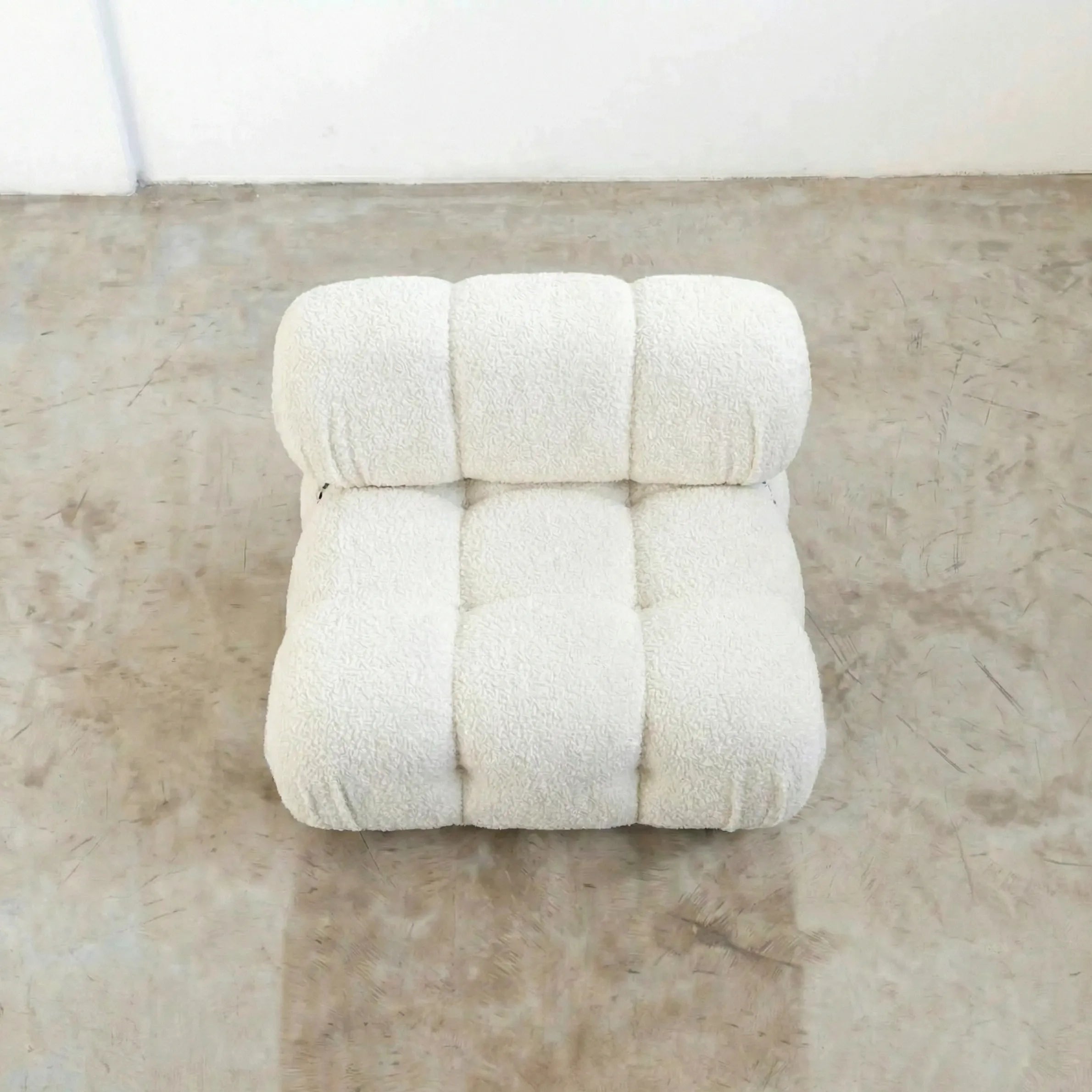 camaleonda dupe armchair in white boucle on a reflective floor with a white wall background