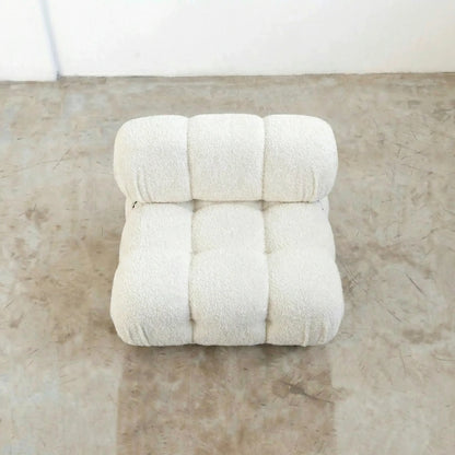 camaleonda dupe armchair in white boucle on a reflective floor with a white wall background