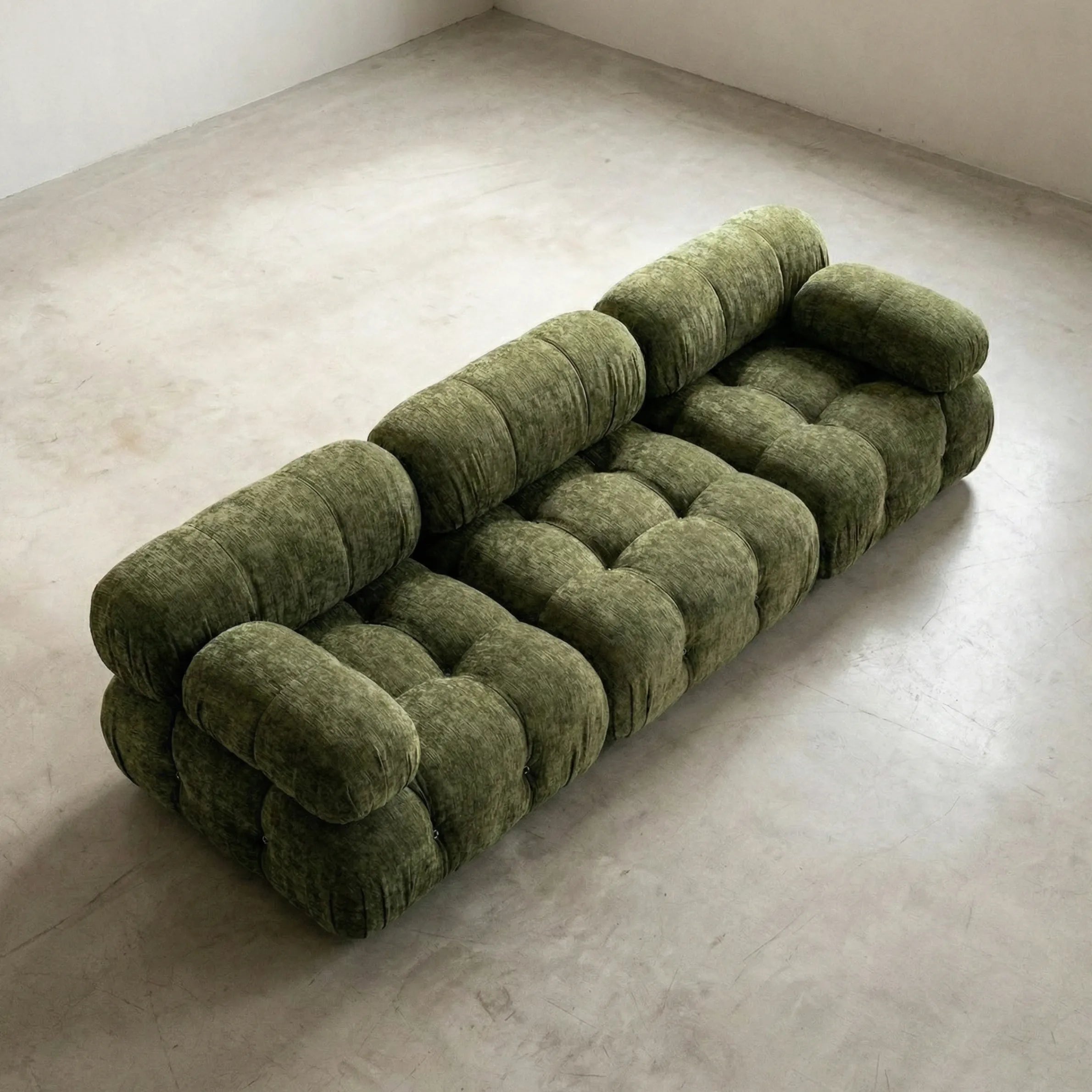 Camaleonda sofa dupe in green chenille on a light gray floor with a white wall background