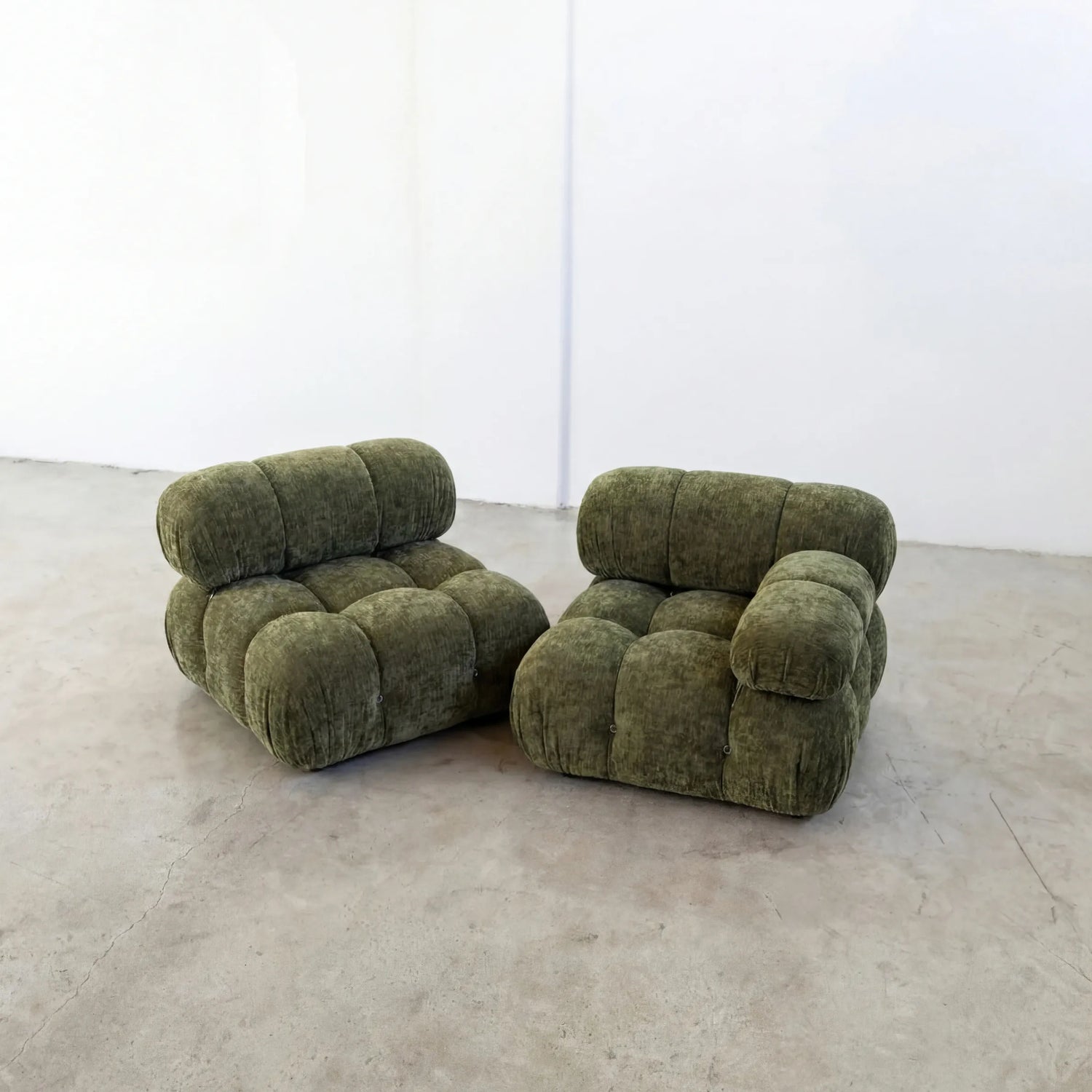 Pair of Camaleonda dupe sofa sections with armrest in green chenille on a concrete floor with a white wall background