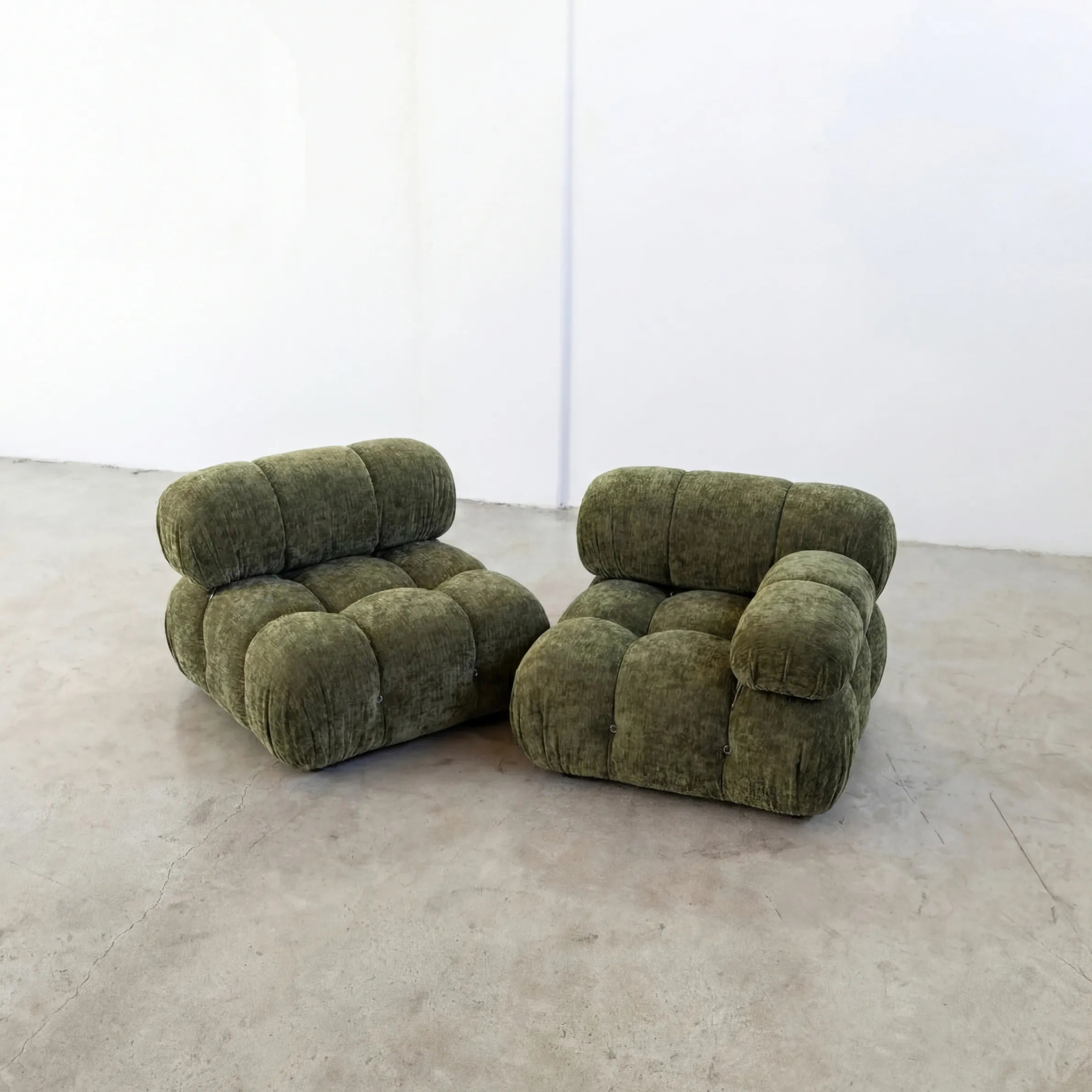 Pair of Camaleonda dupe sofa sections with armrest in green chenille on a concrete floor with a white wall background