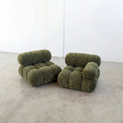 Pair of Camaleonda dupe sofa sections with armrest in green chenille on a concrete floor with a white wall background
