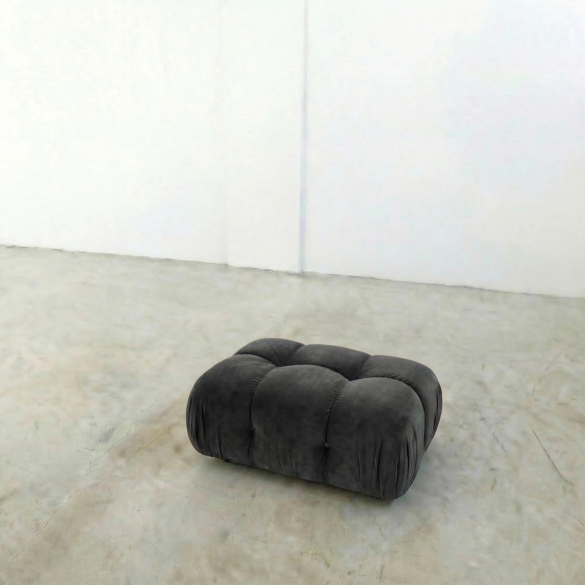 Dark gray camaleonda ottoman alternative on a concrete floor with white walls