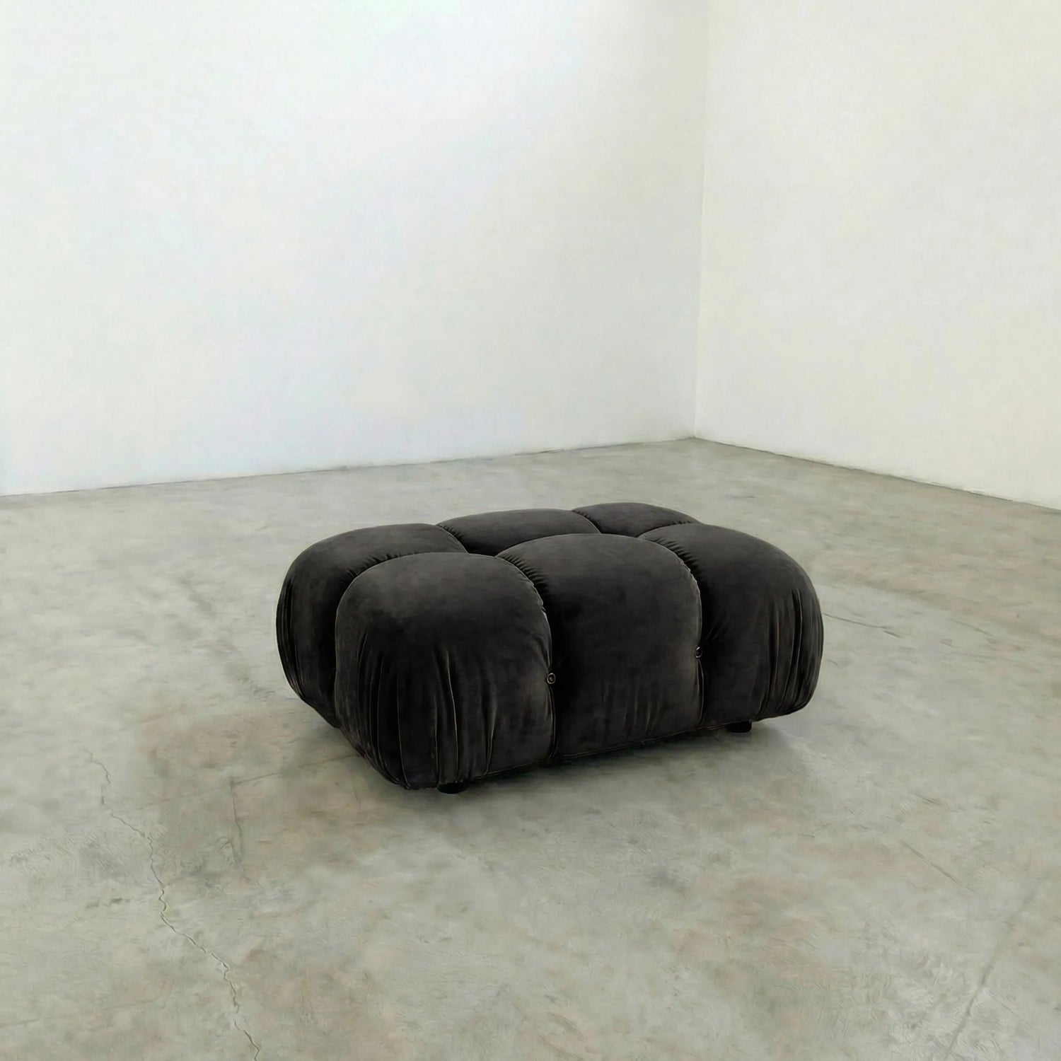 Dark gray camaleonda ottoman alternative on a concrete floor with white walls
