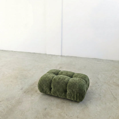 green chenille camaleonda ottoman dupe alternative on a concrete floor with white walls