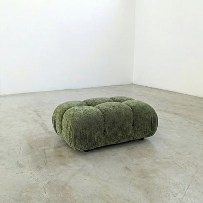 green chenille camaleonda ottoman dupe alternative on a concrete floor with white walls