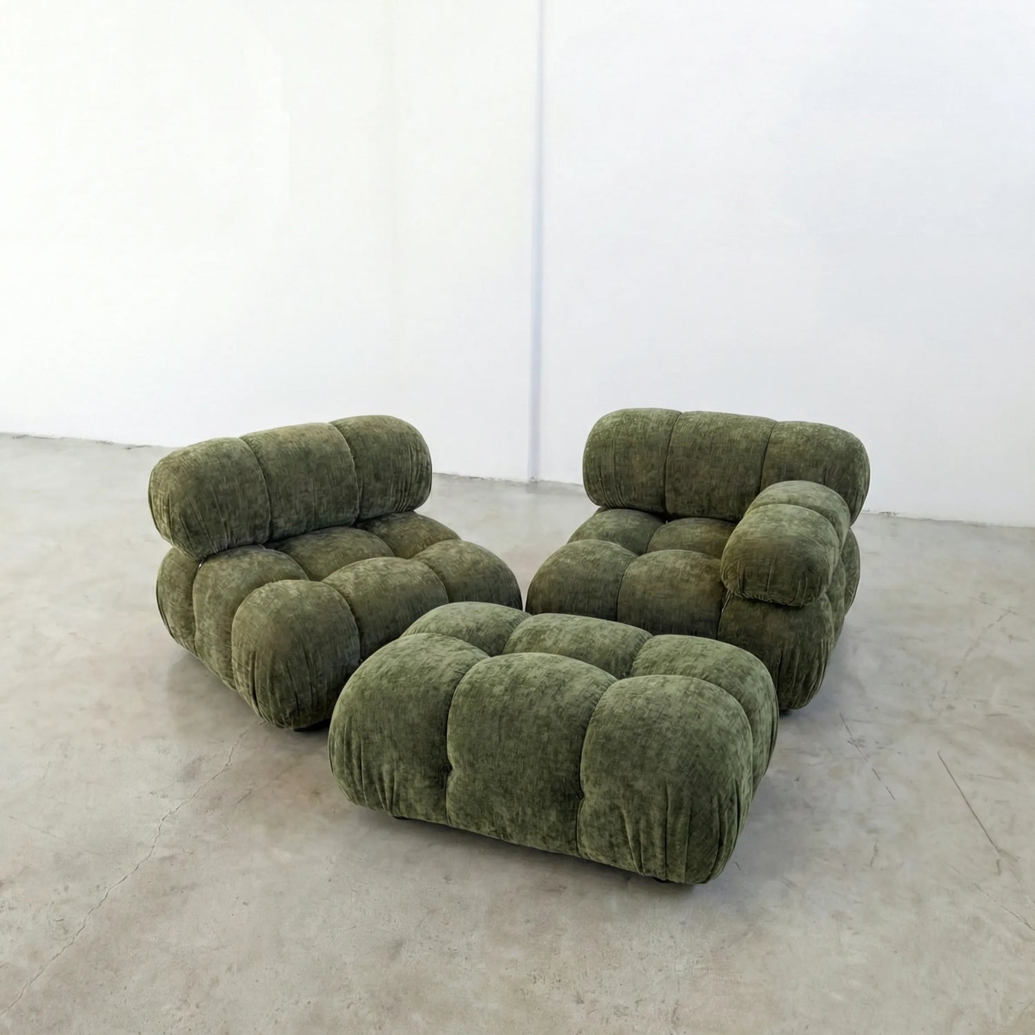 green chenille camaleonda ottoman and armchairs alternative on a concrete floor with white walls