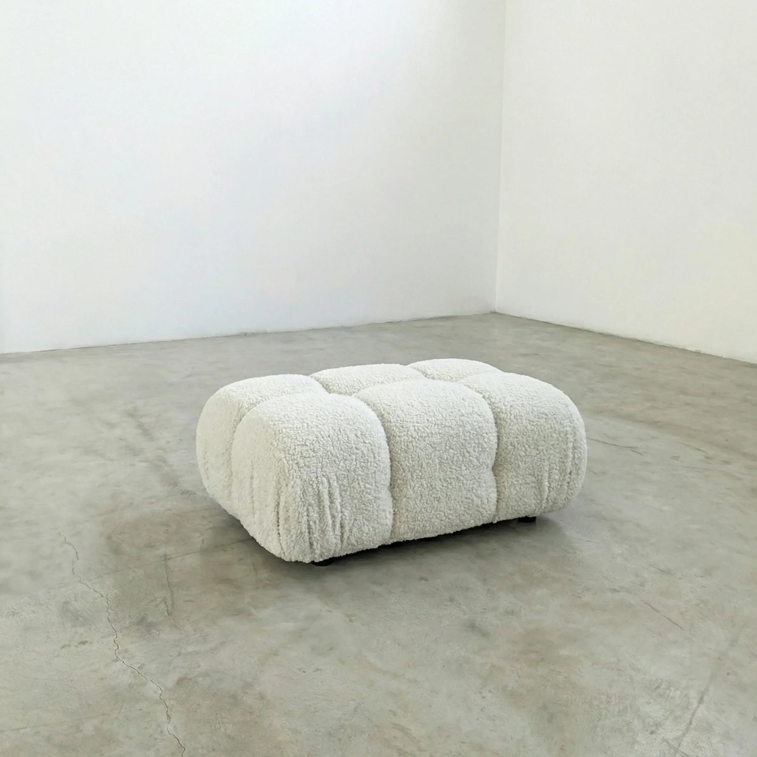 white boucle camaleonda ottoman alternative on a concrete floor with white walls