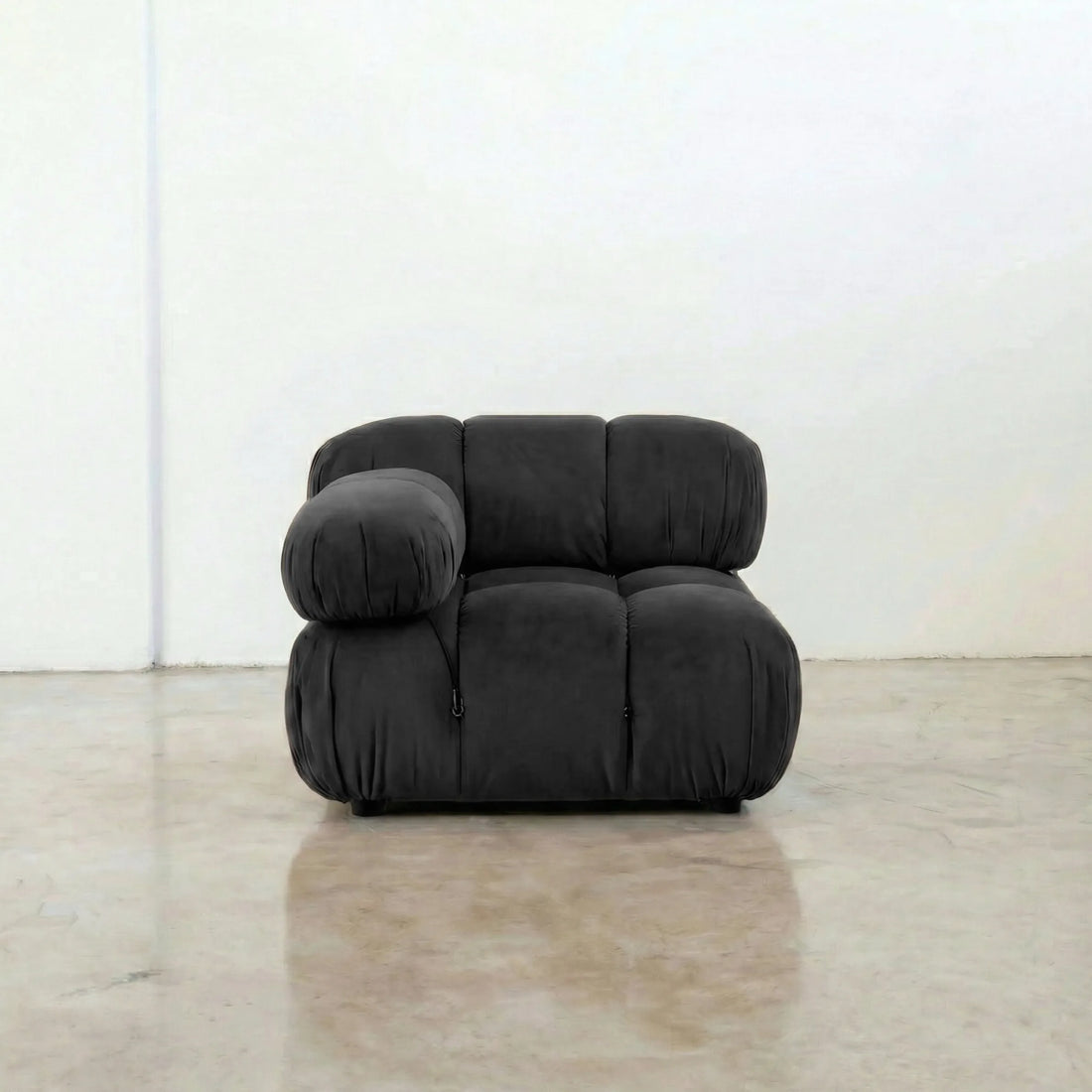 Camaleonda modular sofa section alternative with right armrest in dark grey velvet on a reflective floor with a white wall background