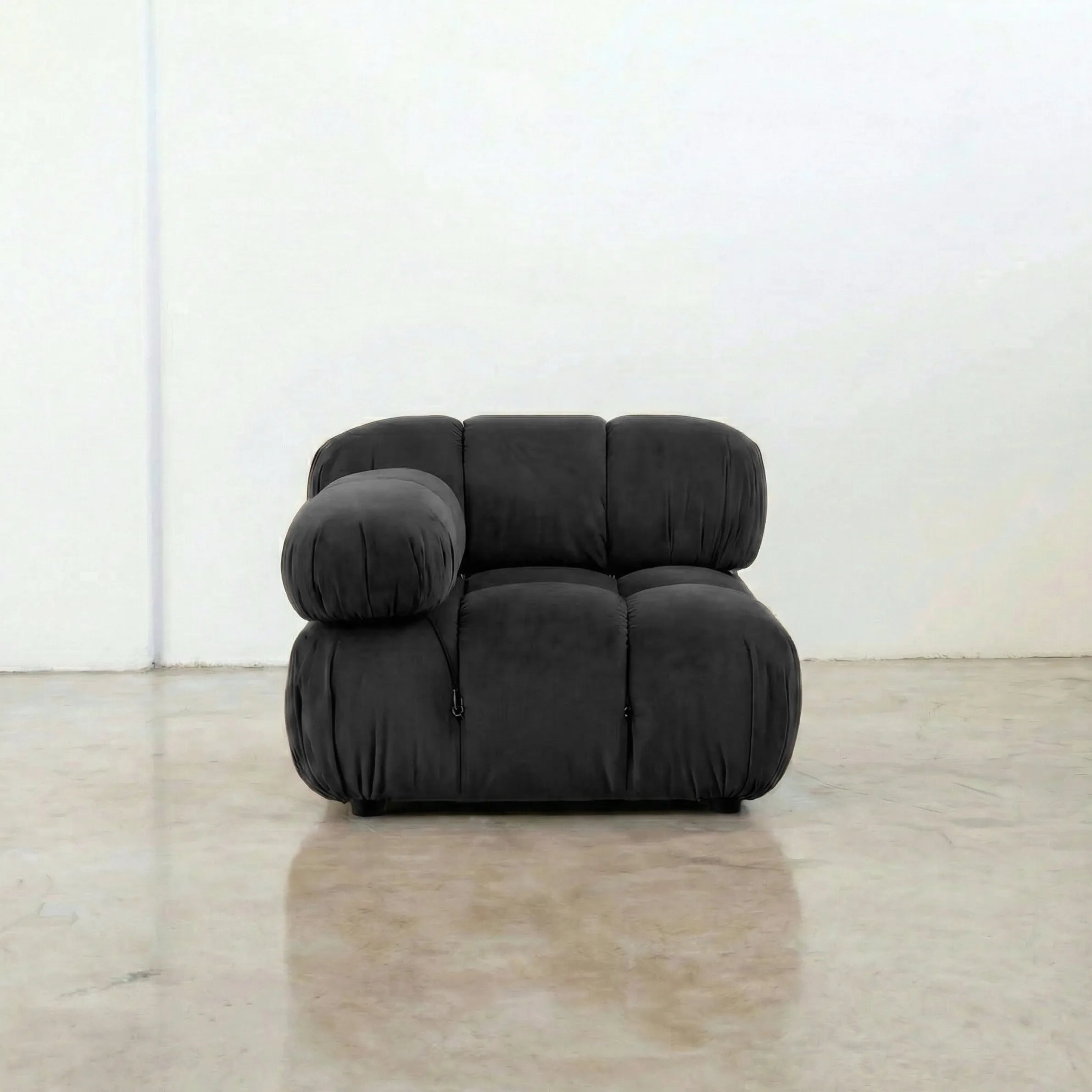 Camaleonda modular sofa section alternative with right armrest in dark grey velvet on a reflective floor with a white wall background