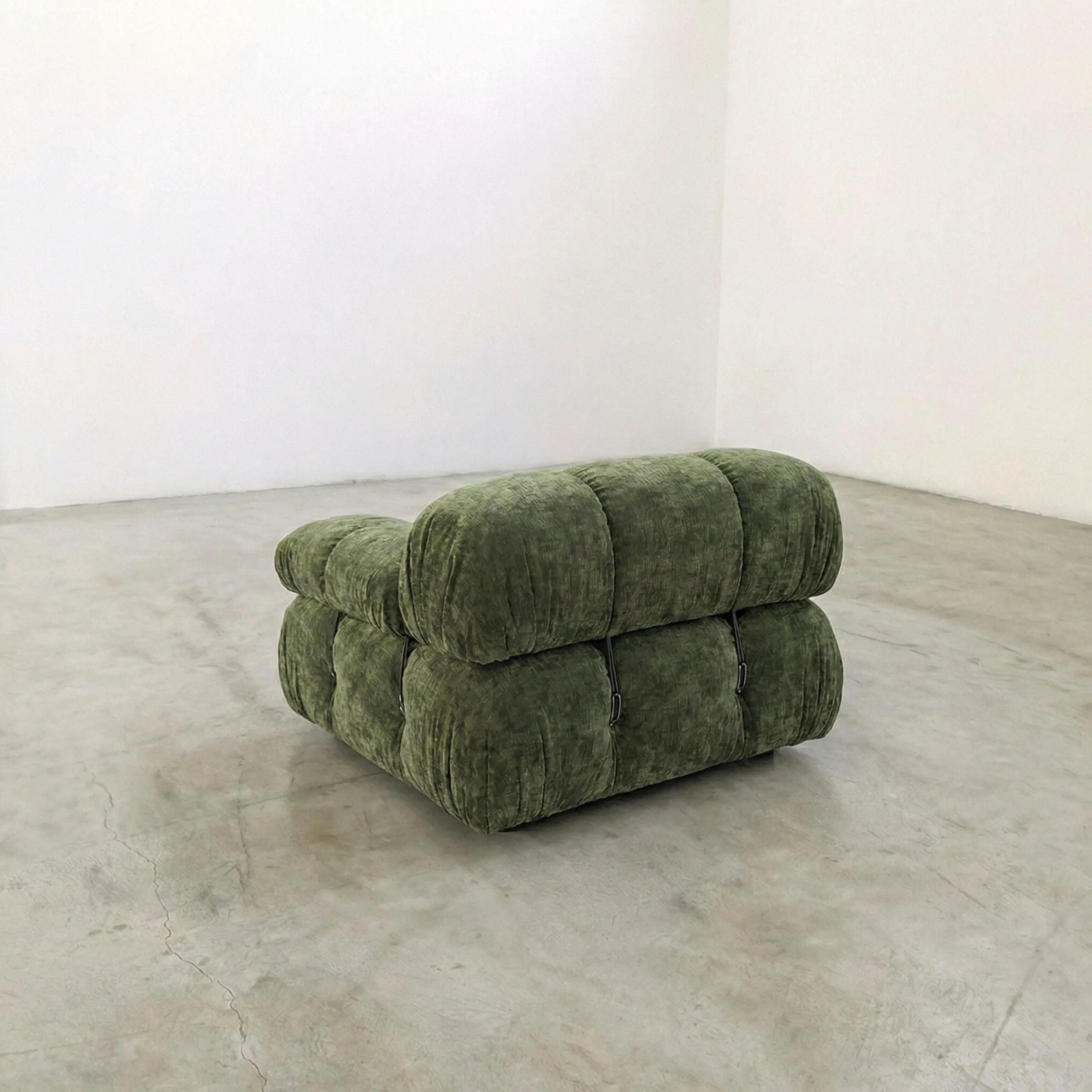 Camaleonda modular sofa section alternative with right armrest in green chenille in a minimalistic room with white walls and concrete floor.