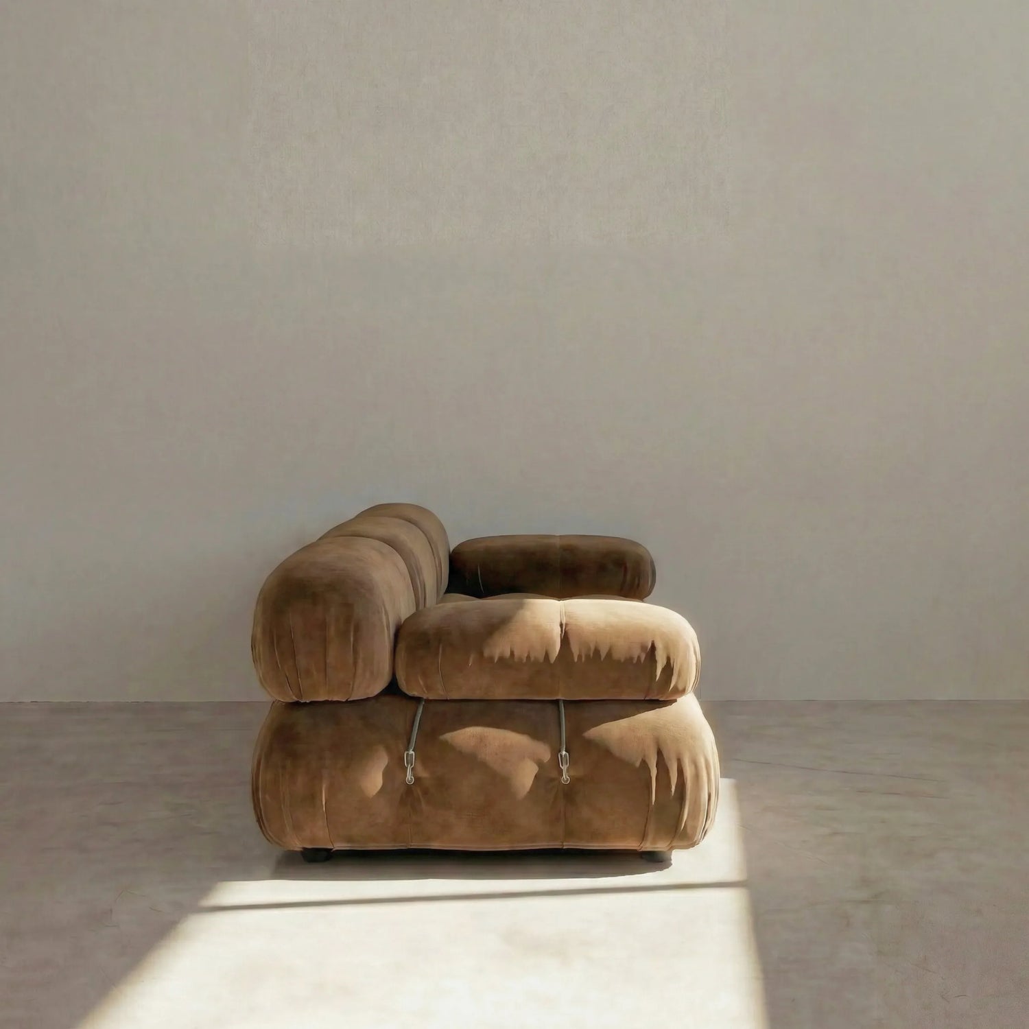 Camaleonda 3 seater modular sofa dupe in brown velvet with tufted upholstery in a minimalistic room with concrete floor and white walls