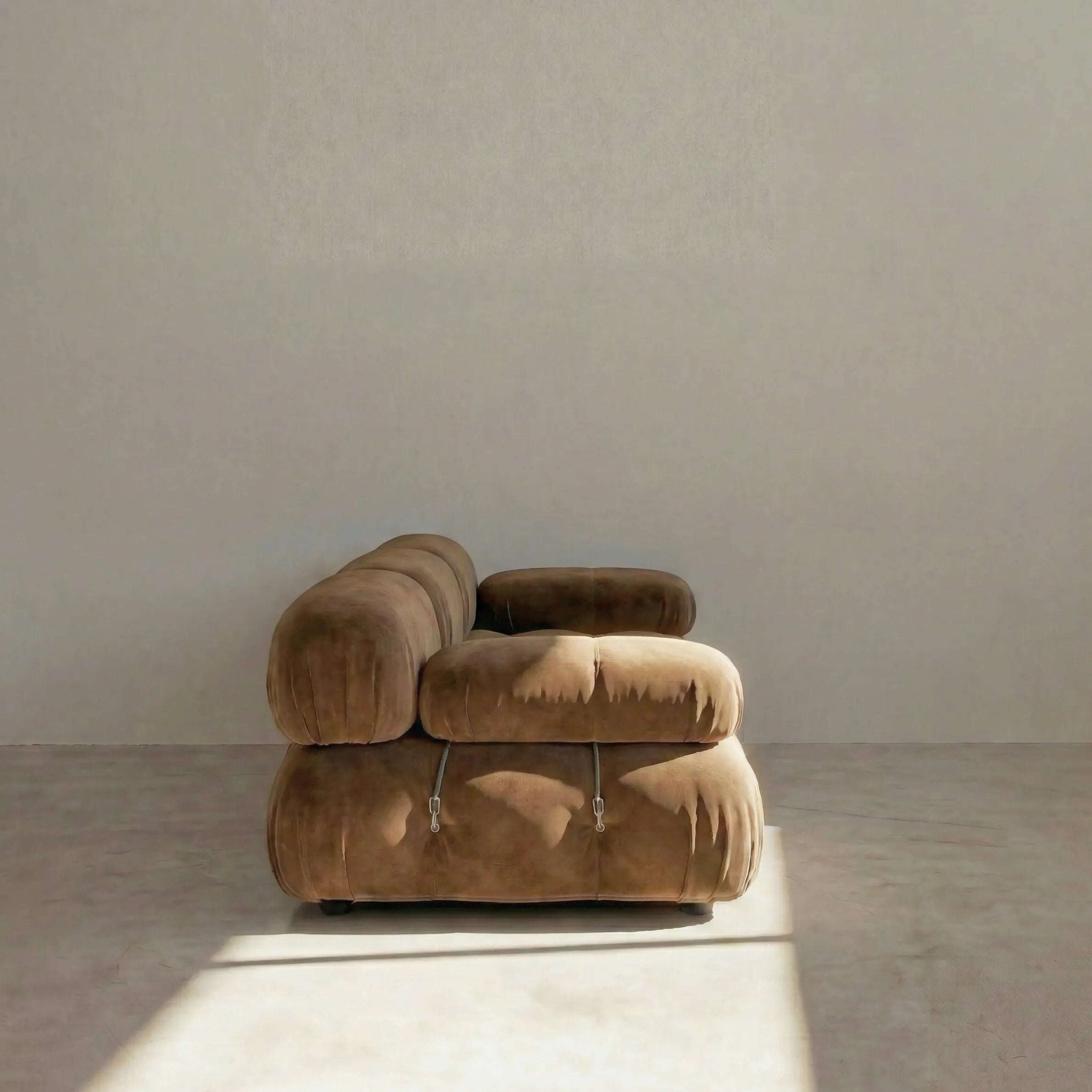 Camaleonda 3 seater modular sofa dupe in brown velvet with tufted upholstery in a minimalistic room with concrete floor and white walls