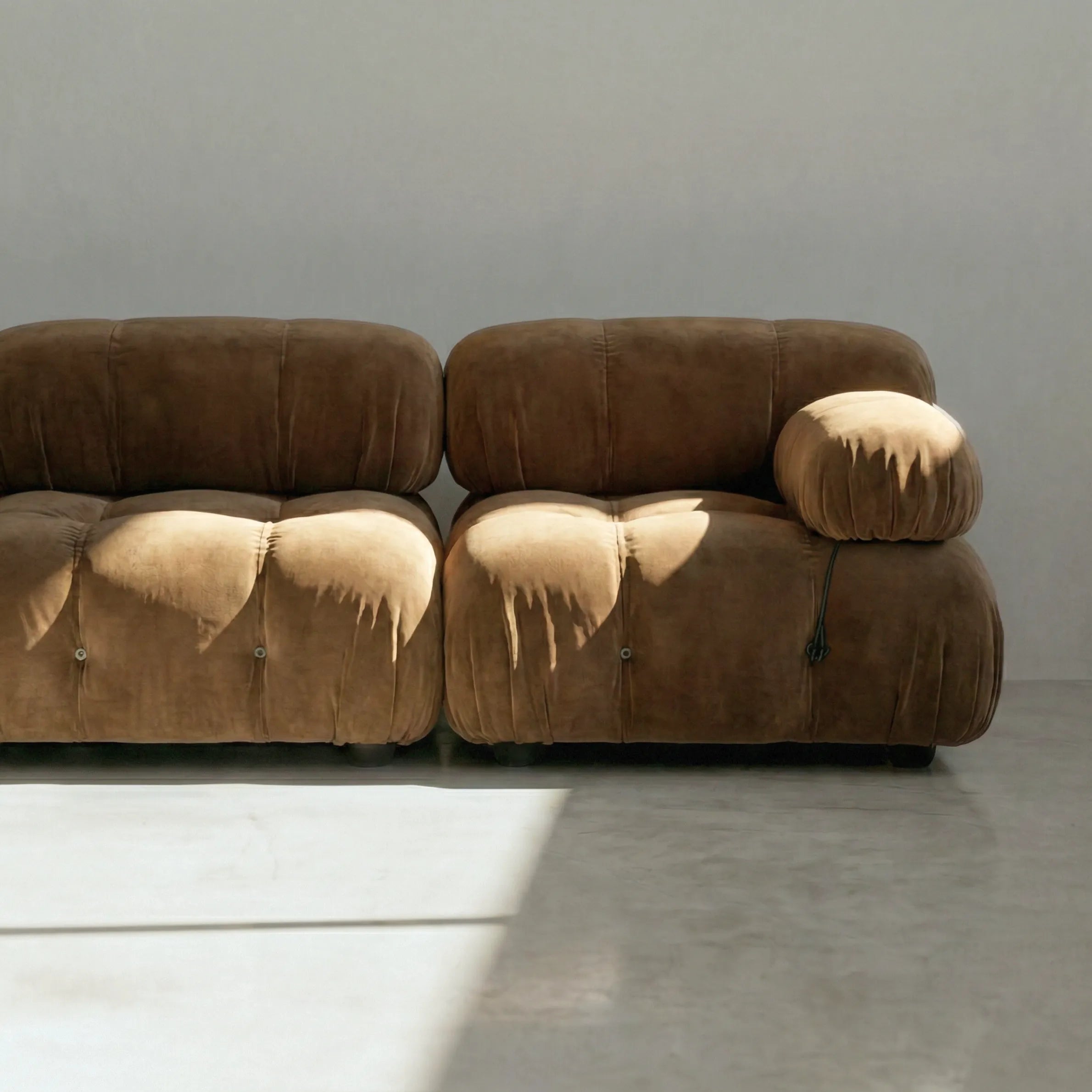 Camaleonda modular sofa dupe in brown velvet with tufted upholstery in a minimalistic room with concrete floor and white walls