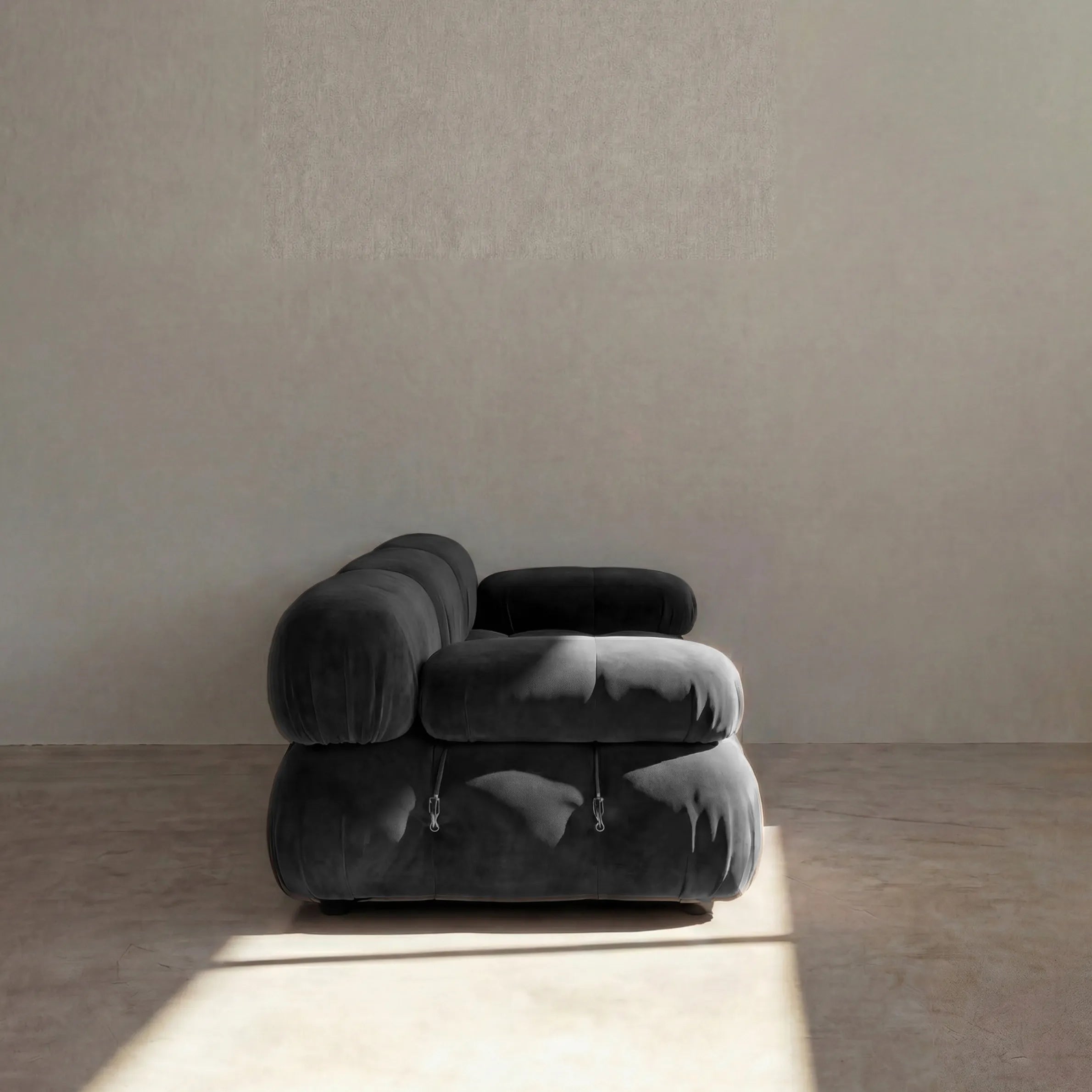 Camaleonda 3 seater modular sofa dupe in dark grey velvet with tufted upholstery in a minimalistic room with concrete floor and white walls