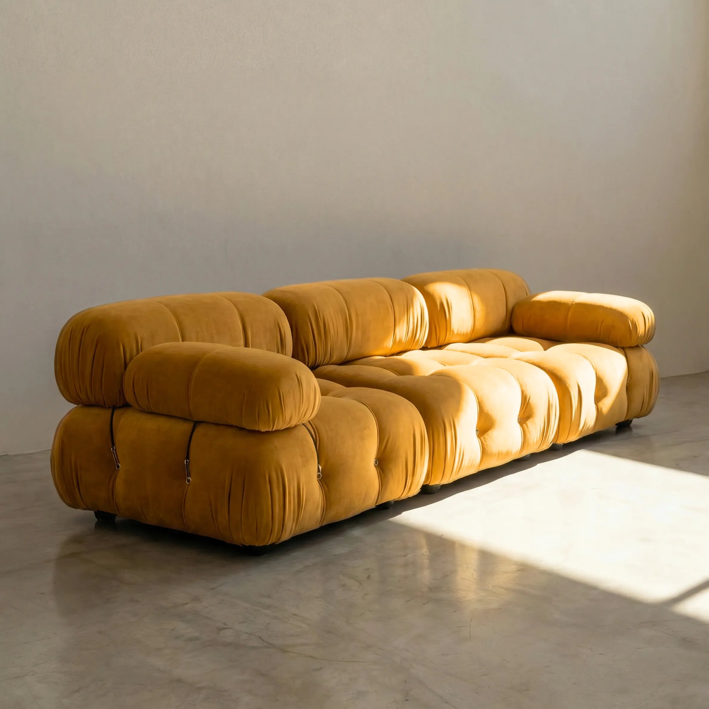 Camaleonda 3 seater modular sofa dupe in mustard velvet with tufted upholstery in a minimalistic room with concrete floor and white walls