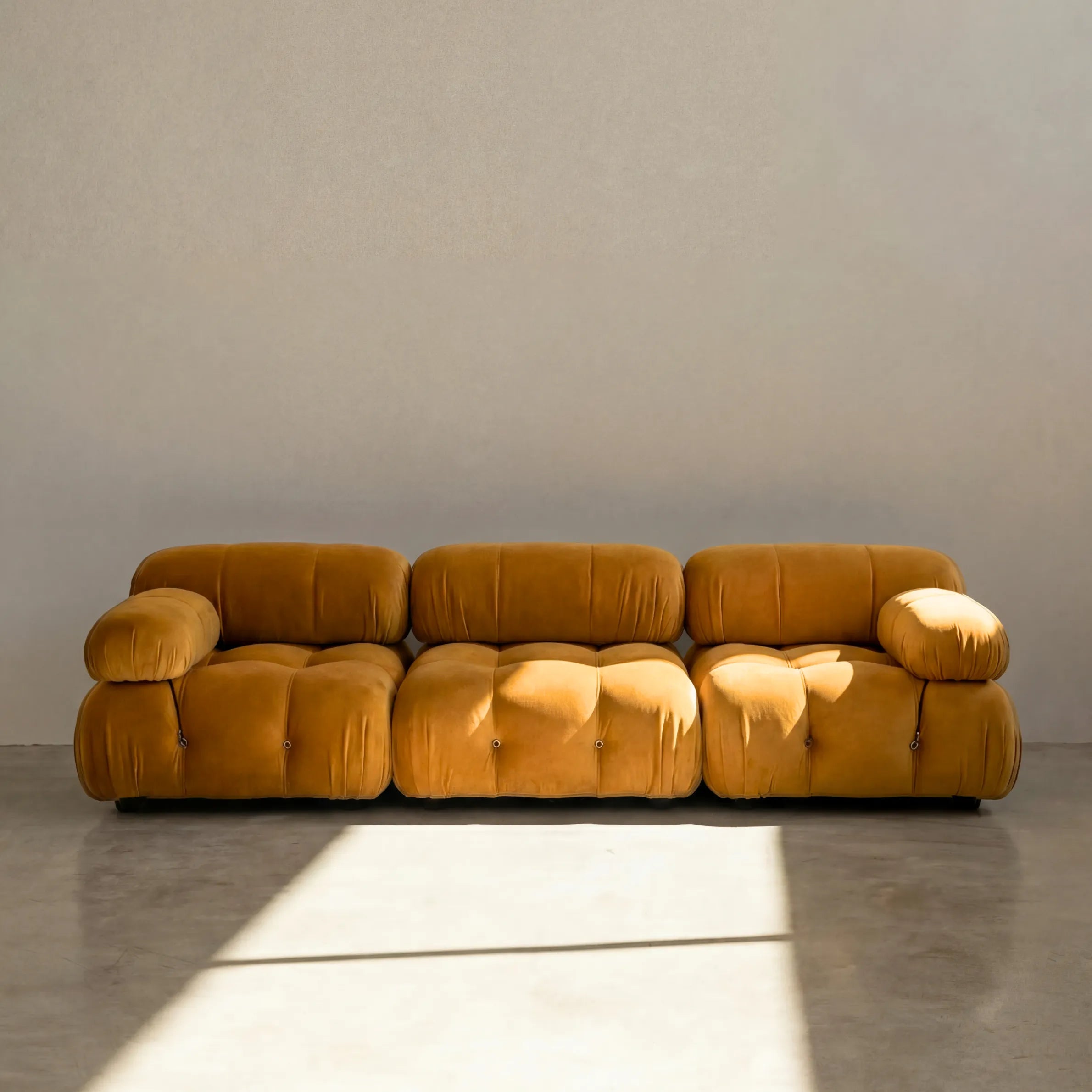 Camaleonda 3 seater modular sofa dupe in mustard velvet with tufted upholstery in a minimalistic room with concrete floor and white walls
