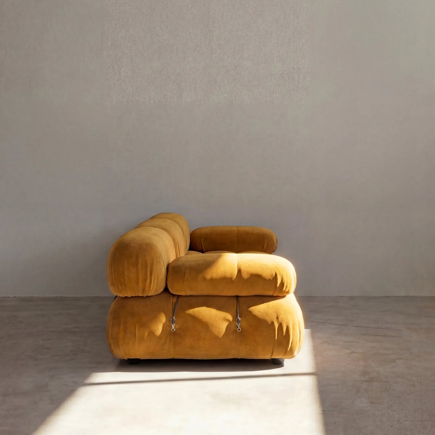 Camaleonda 3 seater modular sofa dupe in mustard velvet with tufted upholstery in a minimalistic room with concrete floor and white walls