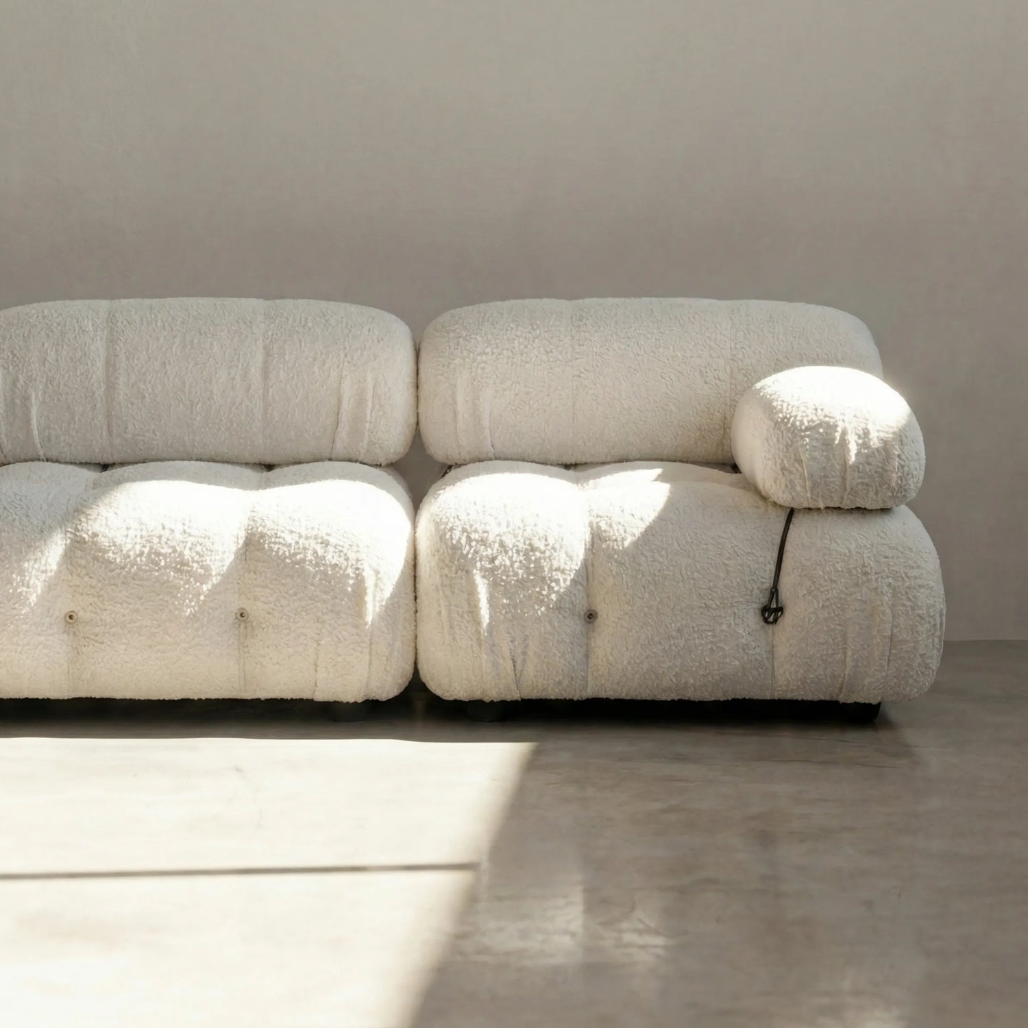 Camaleonda modular sofa dupe in white bouclé with tufted upholstery in a minimalistic room with concrete floor and white walls