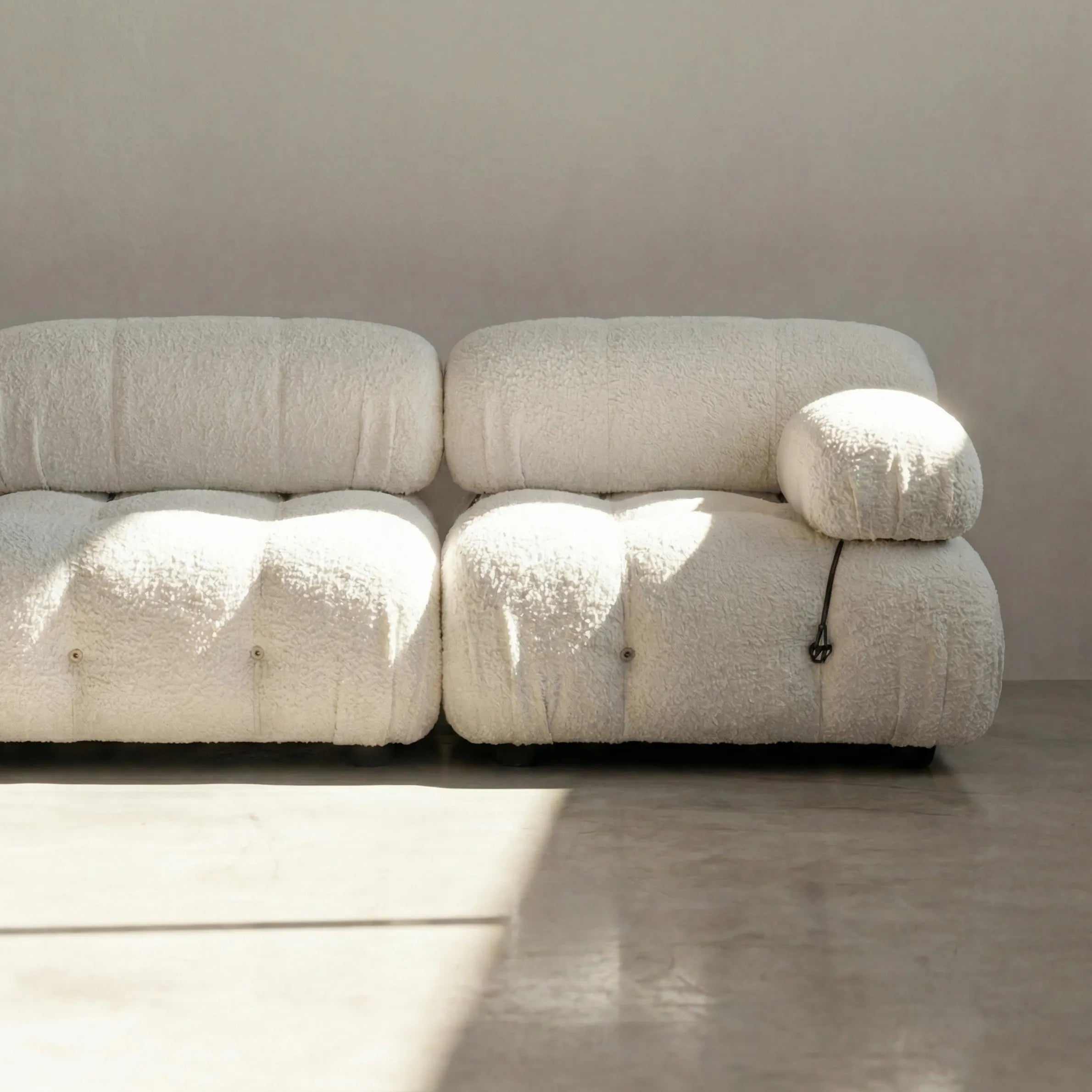 Camaleonda modular sofa dupe in white bouclé with tufted upholstery in a minimalistic room with concrete floor and white walls