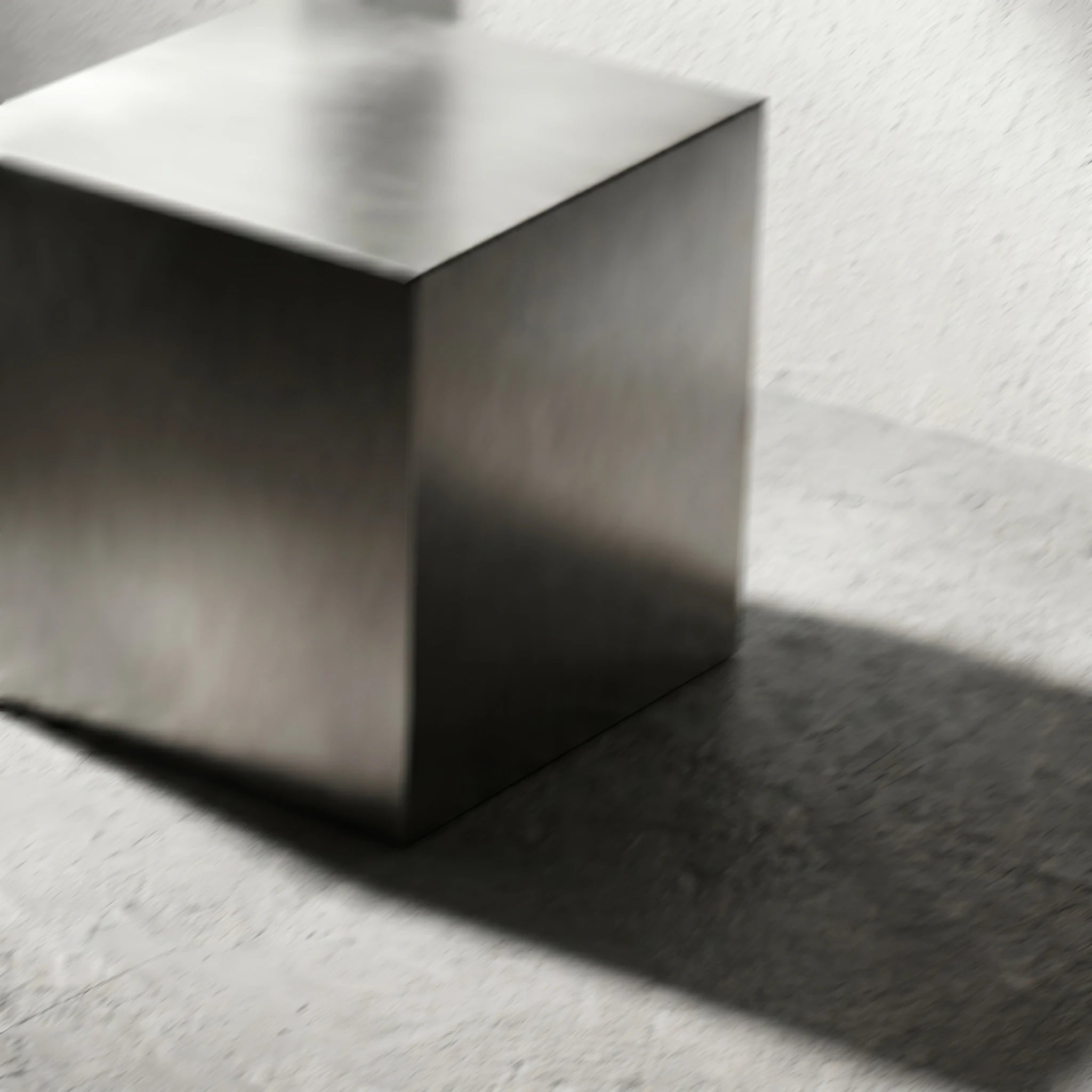 Artistic close-up of the Chrome Steel Cube Table with soft motion blur across the brushed stainless steel surface.