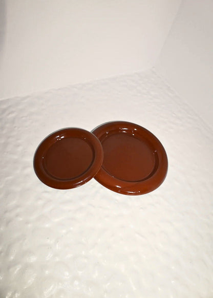 Two brown chunky ceramic plates on a textured white surface inspired by gustaf westmann