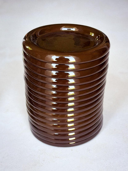 Stack of brown chunky ceramic plates on a white background