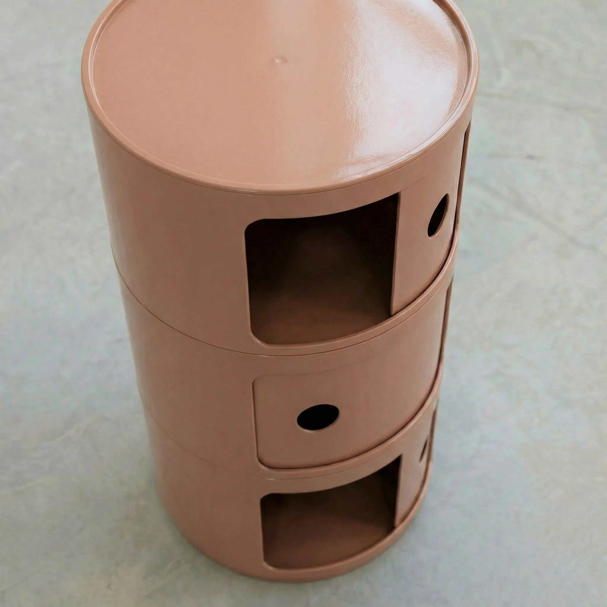 Kartell Componibili dupe round modular storage unit in glossy clay brown plastic with three tiers on concrete floor in white studio setting