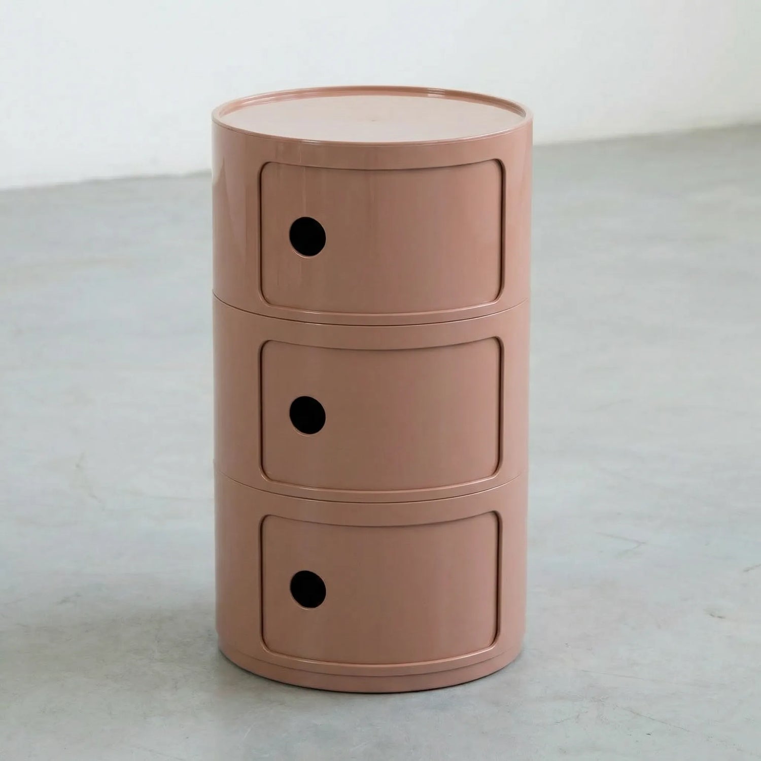 Kartell Componibili dupe round modular storage unit in glossy clay brown plastic with three tiers on concrete floor in white studio setting