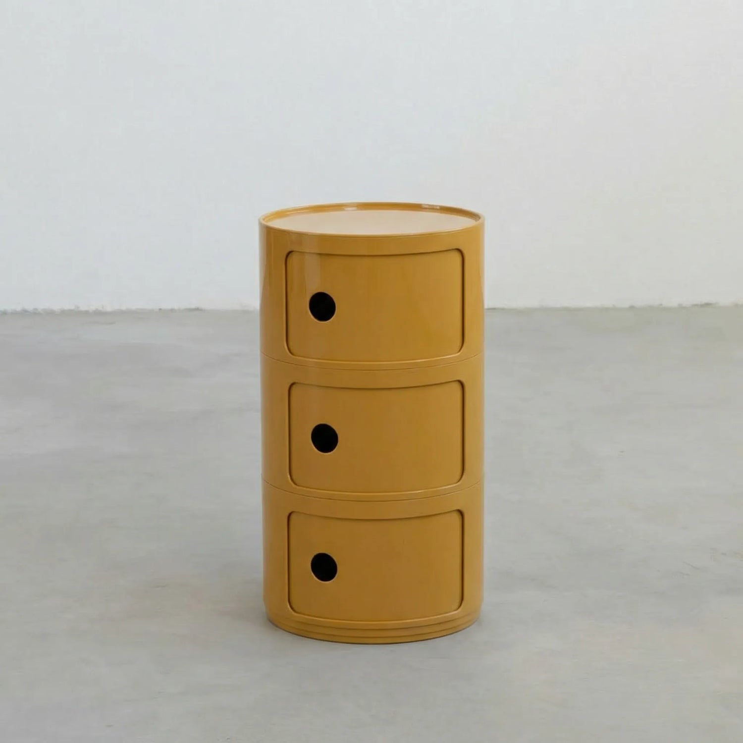 Mustard Yellow glossy round modular storage unit, Kartell Componibili dupe with three tiers in minimalist concrete studio