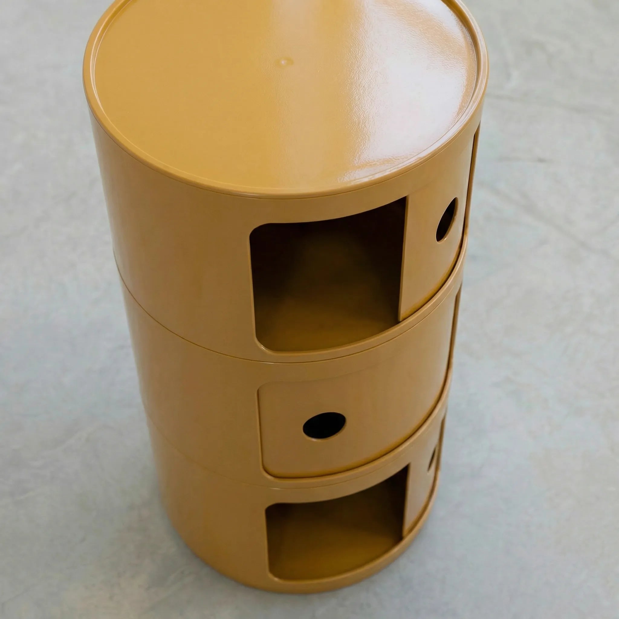 Mustard Yellow glossy round modular storage unit, Kartell Componibili dupe with three tiers in minimalist concrete studio