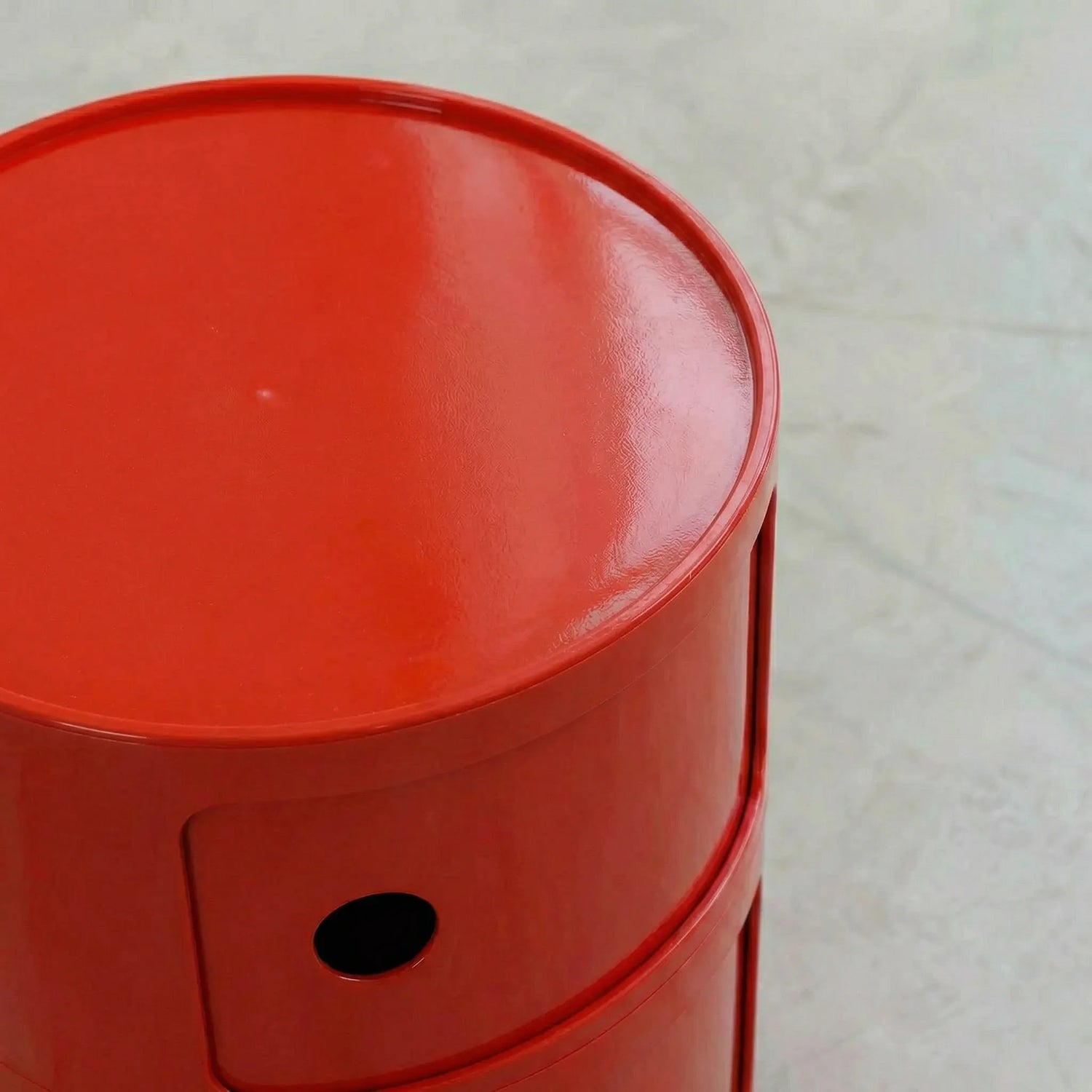 Close-up of a Red glossy round modular storage unit, Kartell Componibili dupe with three tiers in minimalist concrete studio