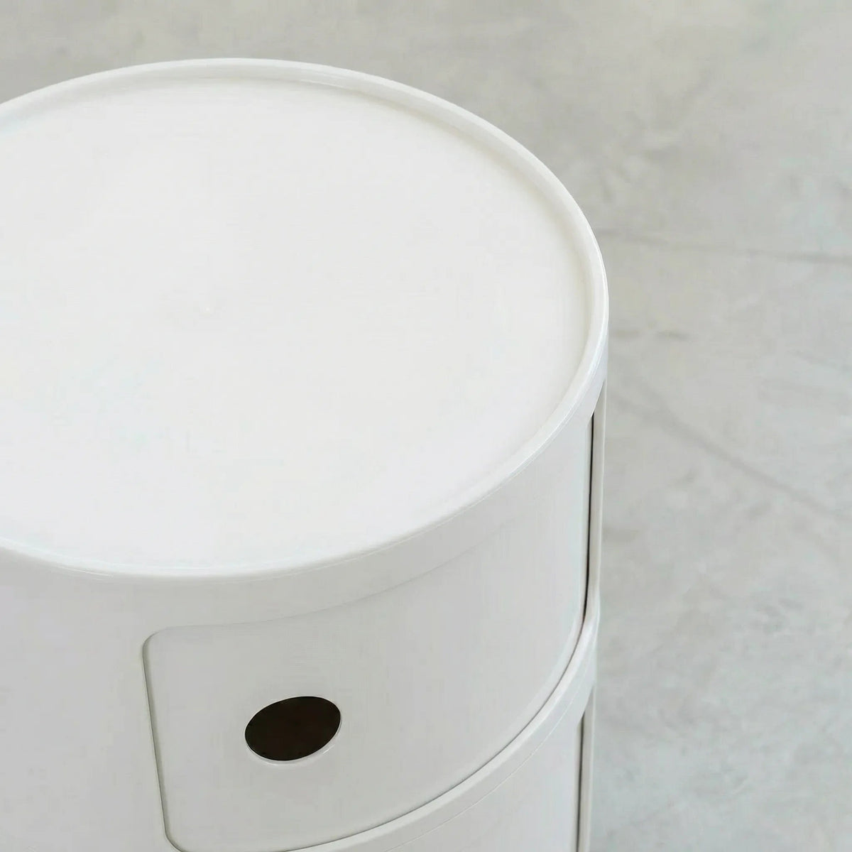 Detail van rond modulair opbergmeubel in wit, op een betonnen vloer.